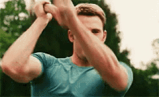 a man in a blue shirt is holding a baseball bat with his hands .