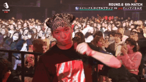 a man stands in front of a crowd with the words round 6 6th match above him