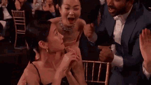 a woman in a red dress is laughing while sitting in a crowd of people at a party .