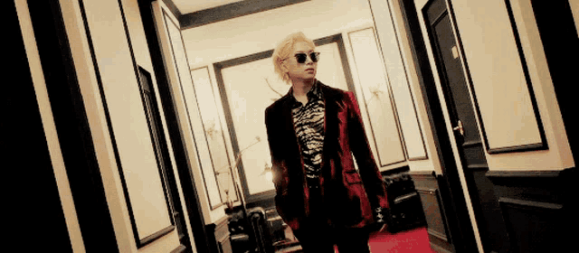 a man in a suit and sunglasses is walking down a hallway .