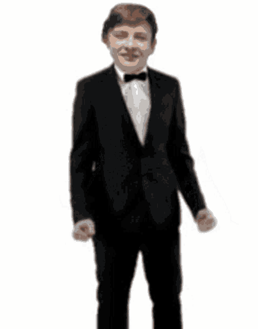 a young man in a tuxedo and bow tie is standing with his arms outstretched