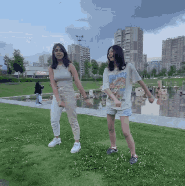 two girls are holding hands in a park and one has a t-shirt that says ' nirvana '