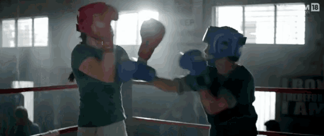 two women are boxing in a ring with a sign that says iron on it