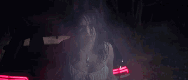 a woman in a white dress is sitting in the back of a car at night .