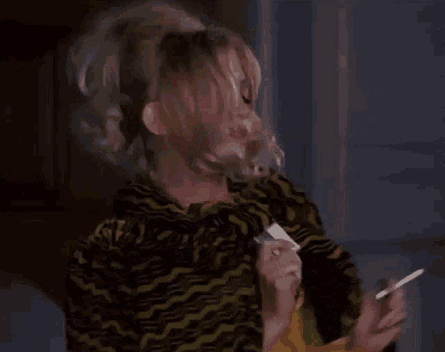 a woman is smoking a cigarette while wearing a yellow and black zebra print jacket .