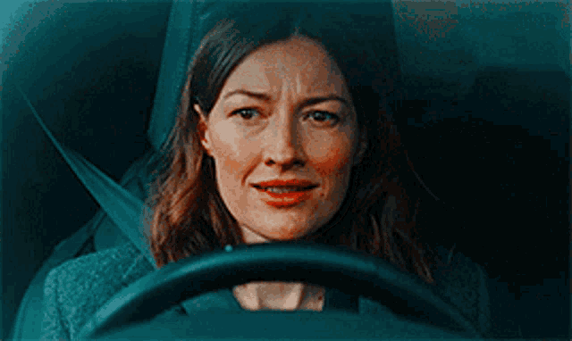 a woman is sitting in the driver 's seat of a car with a serious look on her face