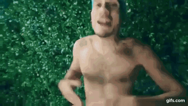 a shirtless man is standing in front of a green wall in a swimming pool .