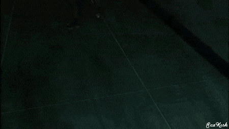 a man in a suit and tie is holding a sword in his hand while standing in a dark room .