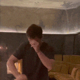 a man in a black shirt is covering his face in a living room