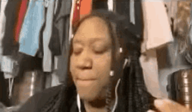 a woman wearing headphones is making a funny face while sitting in front of a closet .
