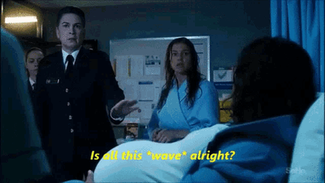 a man in a suit and tie is talking to a woman in a hospital bed who is asking if all this wave alright