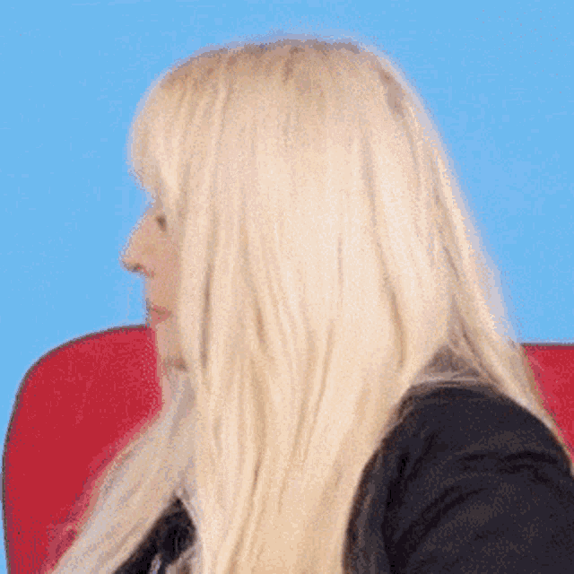 a woman with blonde hair is sitting in a chair