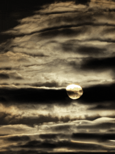a full moon is shining through the clouds