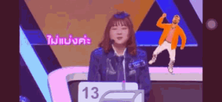 a woman stands at a podium with a sign that says 13