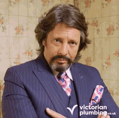 a man in a suit and tie with a victorian plumbing logo