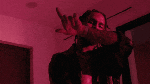 a man with dreadlocks is giving the middle finger in a red room
