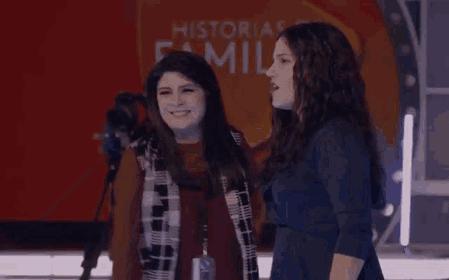 two women standing next to each other in front of a sign that says historias familia
