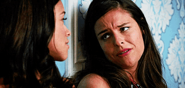 two women are standing next to each other and one of them is making a face .