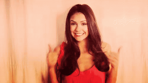 a woman in a red dress is smiling and giving a thumbs up .