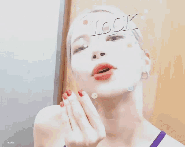 a woman wearing a purple tank top has the word look on her forehead .