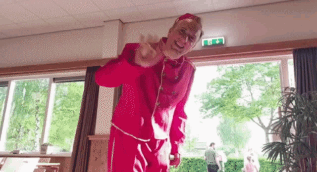 a man in a red suit is standing in front of a window