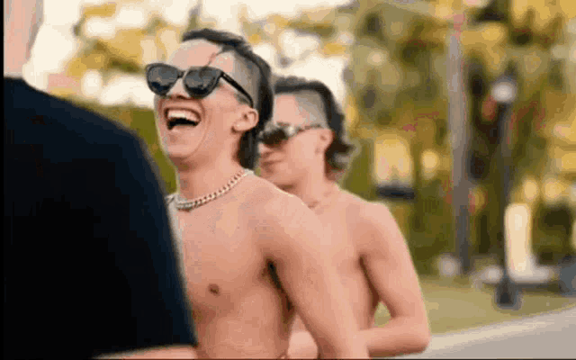 a group of shirtless men wearing sunglasses are laughing together .