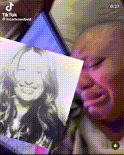 a woman is crying while holding a picture of a smiling woman .