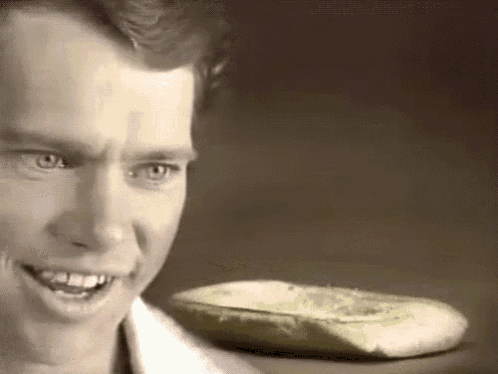 a man is smiling and looking at a piece of bread .