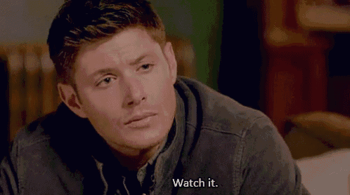 a man is sitting on a couch and talking to someone while wearing a jacket .