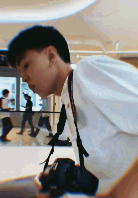 a man in a white shirt is taking a picture with a camera
