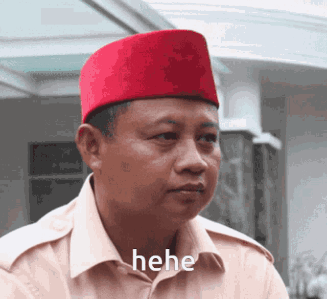 a man wearing a red hat has the word " hehe " written on his shirt