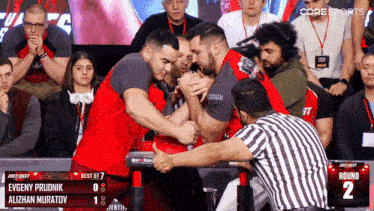 two men are arm wrestling in front of a crowd and the scoreboard shows that the winner is alizhan muratov