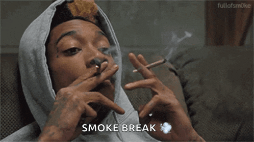 a man in a hoodie is smoking a cigarette and saying smoke break