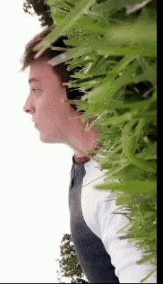 a young man is standing in front of a bush