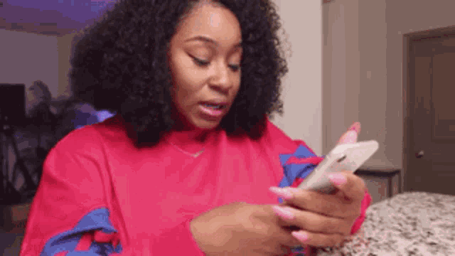 a woman is sitting at a table looking at her phone .