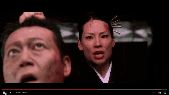 a woman with blood on her face is looking up at a man with blood on his forehead