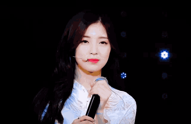 a woman in a white dress is holding a microphone in front of her face .