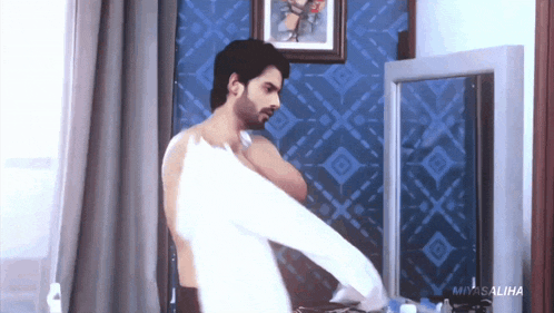 a shirtless man is standing in front of a mirror in a bathroom .