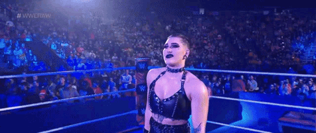 a woman is standing in a wrestling ring wearing a choker and earrings .