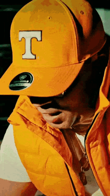 a man wearing a yellow hat with the letter t on the front