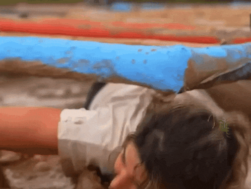 a woman in a white shirt is laying in a muddy field