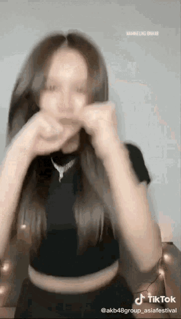 a woman in a black crop top is making a funny face on a tiktok