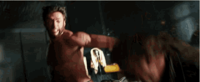 a shirtless man is being punched by another shirtless man in a dark room .
