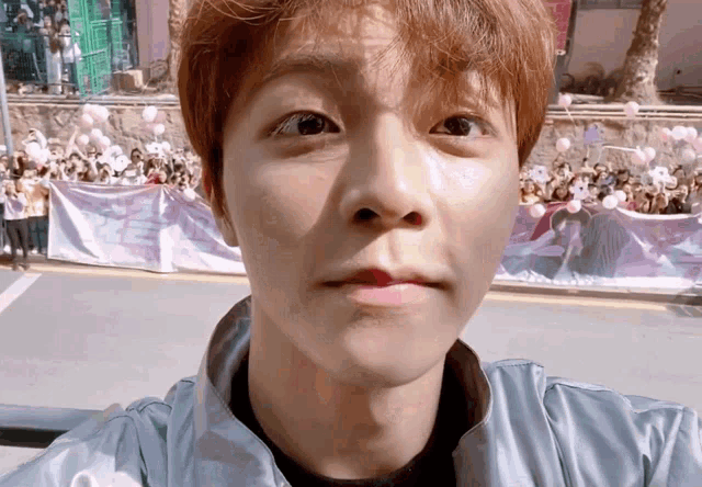 a close up of a person 's face with a banner in the background that says ' i love you ' on it