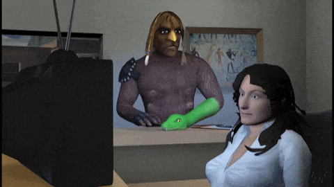 a woman is sitting in front of a television with a man in a native american costume behind her