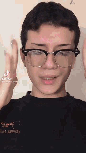 a young man wearing glasses and a black shirt with tiktok written on the bottom