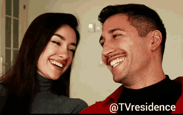 a man and a woman are smiling in front of a screen that says tvresidence