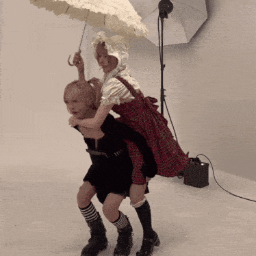 a girl in a plaid dress is holding an umbrella over another girl