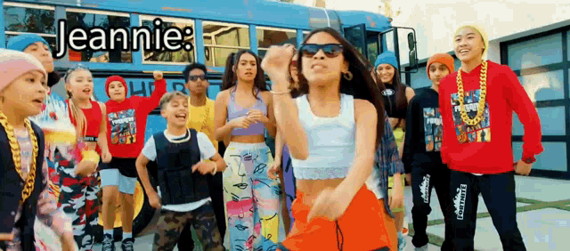 a group of people are dancing in front of a blue school bus .