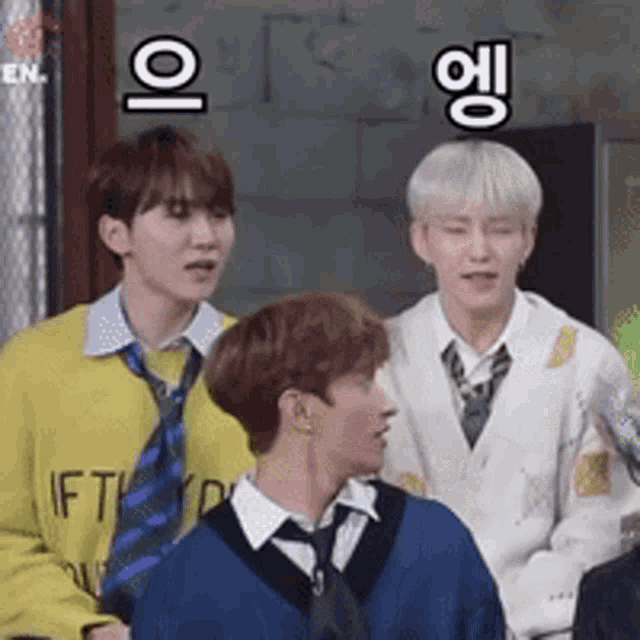 a group of young men are standing next to each other and one of them is wearing a yellow sweater and tie .